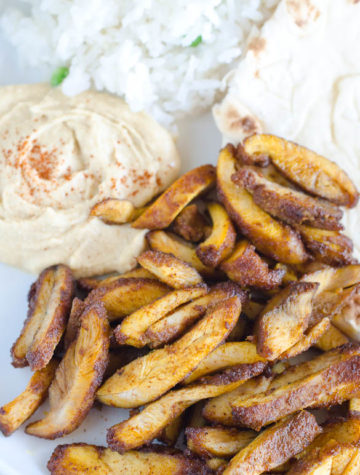 Chicken shawarma on a plate with hummus, rice and pita.