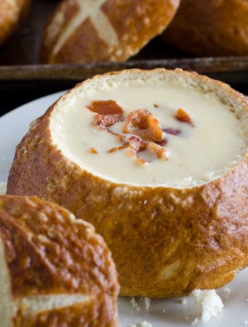 beer cheese soup in a pretzel bowl garnished with bacon